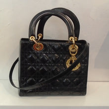 Load image into Gallery viewer, This Dior Patent Leather Medium Lady Dior Bag With Strap has gold hardware, two black carrying handles and a shoulder strap. It has Dior initials in gold attached to one of the carrying handles. The interior of this bag is red.