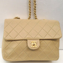 Load image into Gallery viewer, This Chanel Vintage Beige Single Flap 20 Lambskin bag has the diamond stitched pattern with 24 Karat Gold Hardware. It has a long gold shoulder chain with a strip of leather woven between the links. The CC logo front latch is in gold hardware. The inside of this bag is beige also with a pocket.