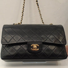 Load image into Gallery viewer, This Chanel Vintage Double Flap 25 Quilted Lambskin bag is black with the diamond stitched pattern. It has the Chanel CC logo on the front clasp of the bag. This bag has gold 24 K gold plated hardware. It has a chain shoulder strap with a black leather strip woven between the chain links. Also, it has a back outside pocket and the interior of the bag is red.