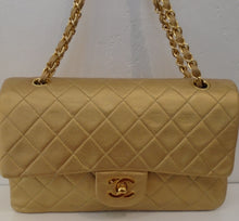 Load image into Gallery viewer, This Chanel Gold Double Flap 25 is 24 Karat Gold plated. The color of the bag is gold and it has a strip of gold leather woven between the gold chain links. This bag has an outside back pocket, gold interior and an inside pocket.