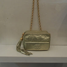 Load image into Gallery viewer, This Chanel Vintage Quilted Gold Lambskin bag has 24 Karat gold plated hardware and a soft leather tassle attached to the front top zipper. The front of the bag is divided into two sections. The top half is in the diamond stitched pattern while the bottom half is solid with the CC logo embroidered in the center.