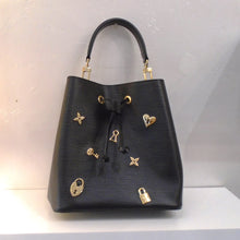 Load image into Gallery viewer, This Louis Vuitton Epi Leather NeoNoe Love Lock is black with gold locks, hearts and flowers similar to monogram. It has a detachable carrying strap and an adjustable detachable shoulder strap. The interior is black with a zippered pocket.