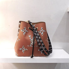 Load image into Gallery viewer, This Louis Vuitton Vintage Reverse Jungle NeoNoe is in shades of camel, brown and cream. One side has large monogram in lepord print against a dark camel background. The other side is small white monogram against a dark and light camel tiger stripe background. It has a black drawstring cord and an adjustable and removable shoulder strap that is black with white small monogram print.