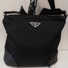 Load image into Gallery viewer, This Prada Vintage Nylon Top Zip Messenger is a black nylon bag but has corner leather reinforcements and a canvas adjustable shoulder strap. The interior of the bag has Prada written in silver repetitiously.