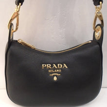 Load image into Gallery viewer, This Prada Vintage Sacca Vitello Phenix Leather With Strap is a black shoulder bag with gold hardware. It has the prada logo in gold on the front center of the bag. The strap is a detachable guitar strap and it has a top zipper.
