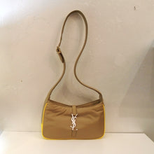 Load image into Gallery viewer, This YSL Light Cork/Yellow Hobo Bag has a long thick adjustable shoulder strap, yellow trim and a white YSL logo on the front of the bag. The top opening of the bag is closed by a strap coming from the back which attaches to the YSL logo that hooks into a loop on the front of the bag. The interior of the bag has the same econyl material.