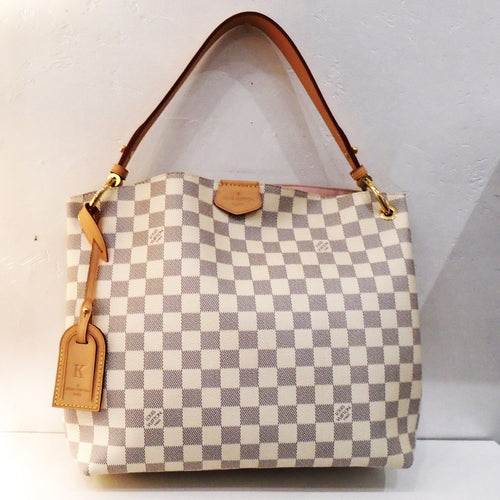 This Louis Vuitton Vintage Damier Azur Graceful PM has camel trim and gold hardware. It has a leather key holder attached to the front of the bag. The interior of this bag is ballerina pink.