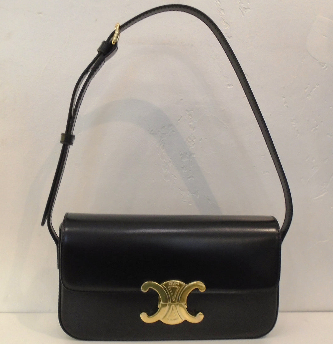 This Celine Claude Shoulder Bag is black with a black shoulder strap and gold hardware. The front latch is the Celine logo with Celine & Paris engraved on it. The interior of this bag is also black.