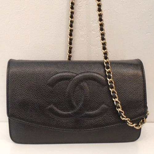 This Chanel Vintage Black Caviar Leather Half Moon WOC has gold hardware and a zippered opening on the back of the bag. The shoulder chain has a black strip of leather woven between the chain links. The front flap comes three quarters the way down the front of the bag with the CC logo embroidered in the center. The flap end has a half moon shape.  The interior of the bag is also black leather and has two zippered  pockets and pockets for holding cards.