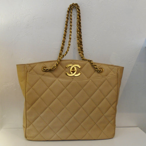 This Chanel Vintage Cream Caviar Turn Lock bag has both a front and back outside pocket. It is 24 Karat Gold Plated which includes the double chain handles with a thin leather strip woven between the links. It also has a zippered pocket on either side of the interior of the bag.