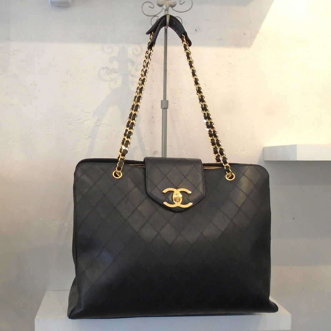 This Chanel Vintage Extra Large Weekender Tote has a diamond stitched pattern and gold hardware. This bag is also called Supermodel Tote because a lot of models use this as an overnight bag. It has a double gold shoulder chain with a thin piece of black leather woven between the links of the chain. The interior of this bag is black and has three sections which includes a middle zippered section with two pocket sections on either side.
