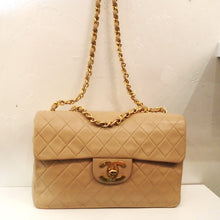 Load image into Gallery viewer, This Chanel Vintage Flesh Tone Maxi 34 Shoulder Bag has  24 Karat Gold Plated Hardware and is in the diamond stitched design. It has a long shoulder chain with a thin strip of  leather woven between the links.  The clasp is on a lip on the flap with the CC logo as the latch. The interior of the bag is in the same flesh tone shade.
