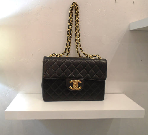 This Chanel Vintage Jumbo Collectable has 24 Karat Gold trim. The CC logo clasp has an indented square within the C. It has a double shoulder chain with a black leather strip woven between the links. The bag is black diamond stitched lambskin. It has a pocket on the back of the bag. The interior of this bag is burgandy.