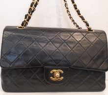Load image into Gallery viewer, This Chanel  Vintage Lambskin Double Flap 25 is black with diamond stitching. It has 24 Karat Gold hardware which includes the logo on the front clasp and the double shoulder chain. The shoulder chain also has a leather strip woven between the chain links. The interior of this bag is red.
