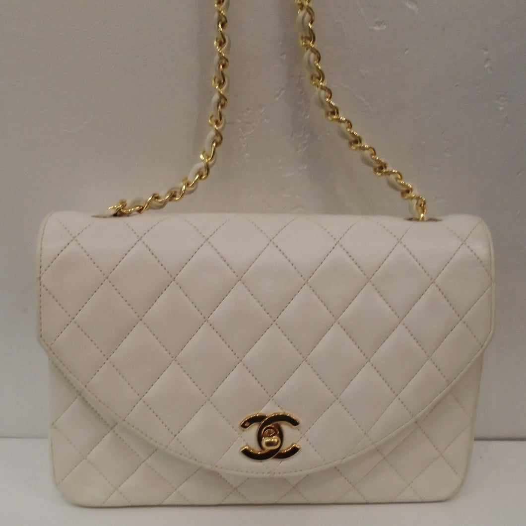 This Chanel Lambskin Pearl White Flap has the diamond stitched design and 24 Karat Gold plated hardware. It has a chain shoulder strap with a thin white leather strip woven between the chain links. The clasp is the CC logo in gold.