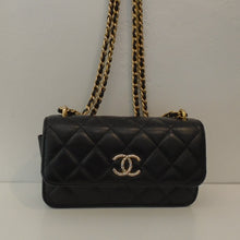 Load image into Gallery viewer, This Chanel Vintage Mini WOC is black with the original Chanel diamond stitching. It has a half flap with the Chanel logo on the lower center of the flap. This bag has a double gold shoulder chain with a black leather strip woven between the links. The interior of this bag is gold with a zippered pouch.
