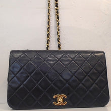 Load image into Gallery viewer, This Chanel Vintage Navy Lambskin Full Flap is in the stitched diamond pattern with gold toned hardware. It has a shoulder chain which has a thin strip of leather braided though the chain. The interior of this bag is red.
