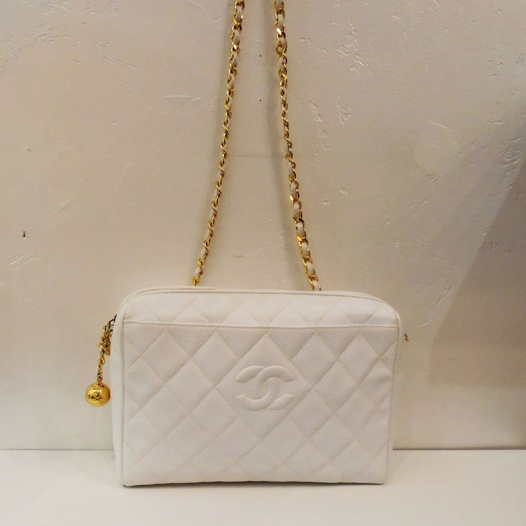 This Chanel Vintage Pure White Caviar Shoulder Bag has a zippered opening and gold hardware. The zipper has a gold ball attached to it. This bag has a gold shoulder chain, the diamond stitched pattern and the CC logo stitched in the center of a stitched diamond on the front of the bag. The interior is the same white shade as the outside of the bag.