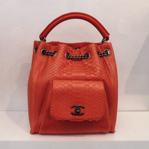 This Chanel Vintage Red Python Urban Backpack is patterned liken to snake skin. It has dark silver hardware which includes the Chanel logo front clasp. The bag has a small pouch on the front of the bag and a thick handle on the top. A chain runs through the top of the bag through rings and follows to the back which are used as back straps for the backpack.