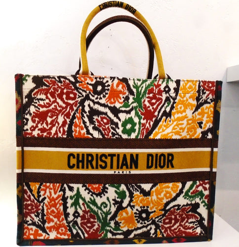 This Christian Dior Tapestry Book Bag is floral multicolored. It has a strip across the middle with the name Christian Dior embroidered on it.