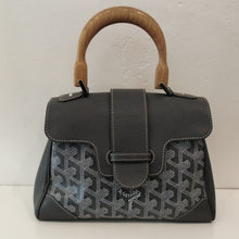 Load image into Gallery viewer, This Goyard Grey Mini Siagon bag has a wooden carrying handle and Goyard written under the flap. The interior of this bag is an orange-gold.
