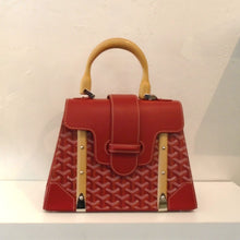Load image into Gallery viewer, This Goyard Red Medium Saigon With Strap has the Goyard design with solid red corners and top flap. It has a thick middle strap that fits into a loop on the front of the bag. The carrying handle is wooden along with to front strips on the front of the bag under the top flap. The interior of this bag is yellow.
