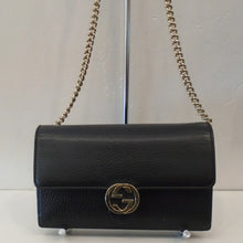 Load image into Gallery viewer, This Gucci Vintage Black WOC has gold hardware and the front clasp is in the interlocking logo pattern. The interior of this bag  has a zippered compartment and a 16 card credit card holder. It is the same black leather interior as the outside of the bag. The shoulder chain has a leather shoulder guard.
