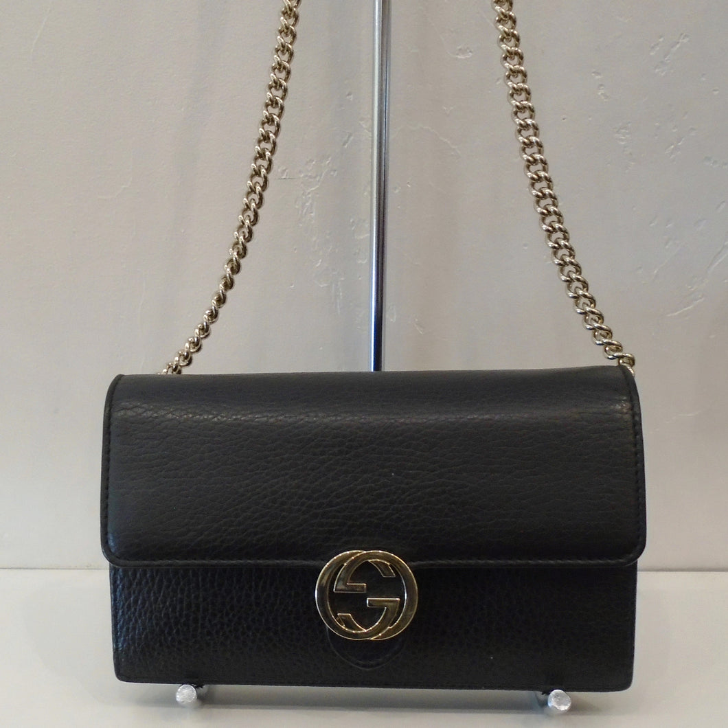 This Gucci Vintage Black WOC has gold hardware and the front clasp is in the interlocking logo pattern. The interior of this bag  has a zippered compartment and a 16 card credit card holder. It is the same black leather interior as the outside of the bag. The shoulder chain has a leather shoulder guard.