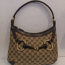 Load image into Gallery viewer, This Gucci Vintage  Canvas Brown Snaffale Hobo has a brown Gucci pattern with dark brown trim and carrying handle. It has a large snaffale across the front of the bag made of dark brown leather and gold ring bits. The interior of this bag is also dark brown.
