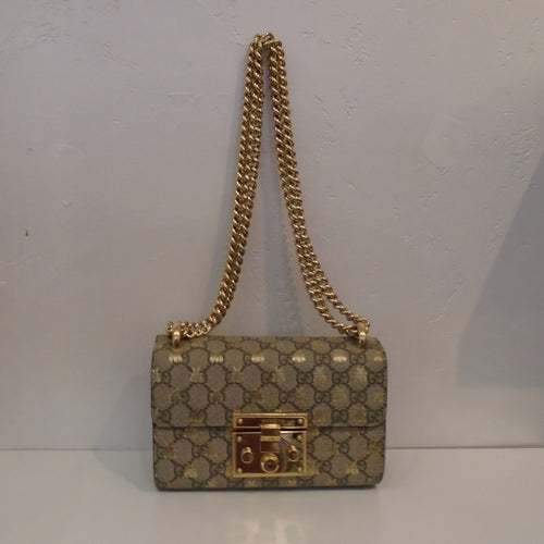 This Gucci Vintage Guccissima Small Gold Bee Padlock 2 Way Bag is in the Gucci pattern with golden bees withing the pattern. It has a gold front latch and double gold shoulder chain. It has a black back pocket and the interior is gold.
