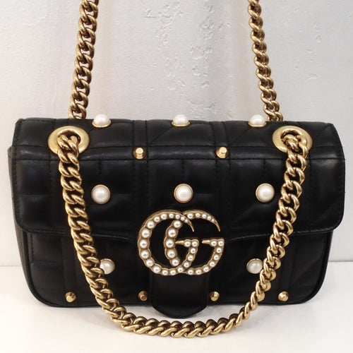 This Gucci Marmont Faux Pearl Shoulder Bag is black with faux pearls and gold studs on the front and back of the bag. It has the Gucci Logo in gold with faux pearls on the logo in the center front of the bag and has a heavy double gold shoulder chain. The interior of the bag is a soft cream.