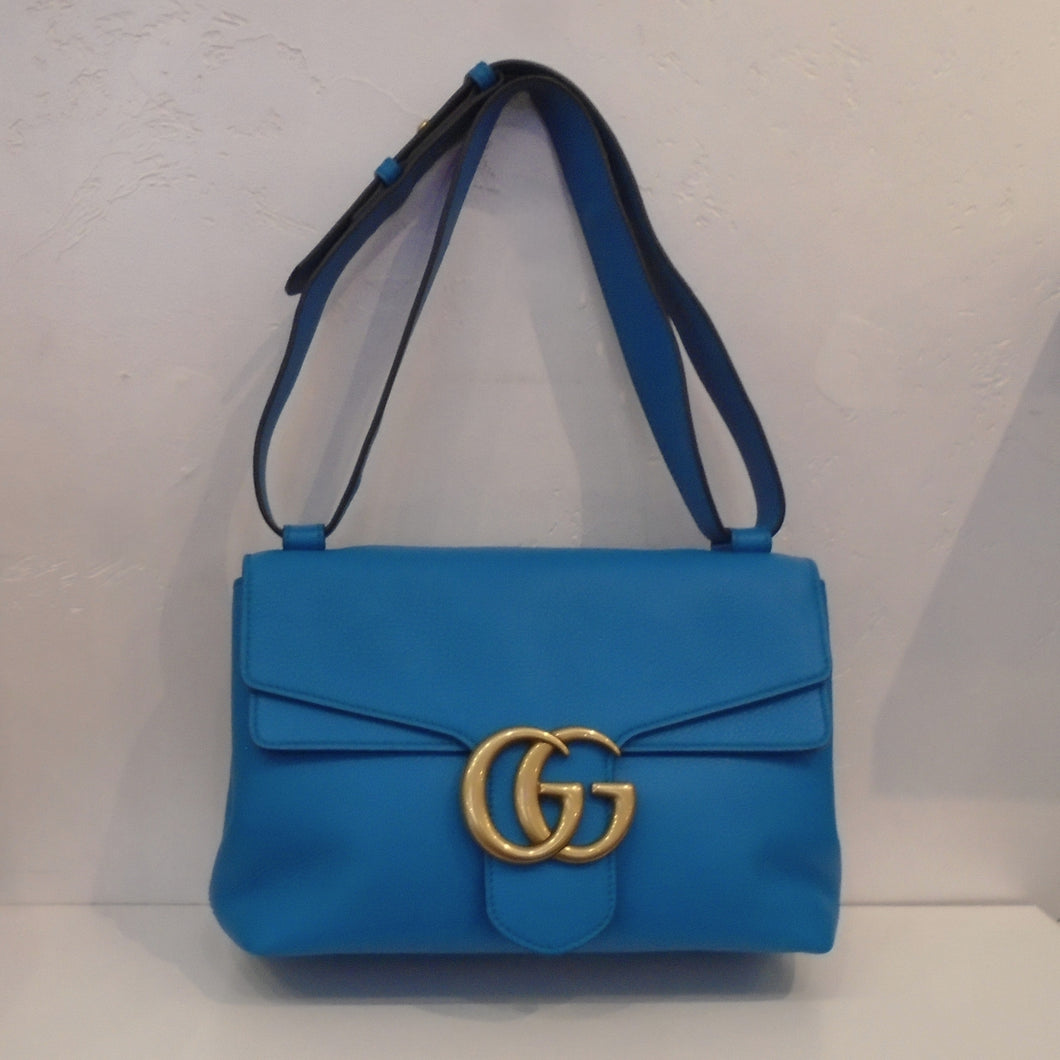 This Gucci Vintage Marmont Shoulder Bag is sky blue with gold hardware which includes the Gucci logo on the front latch of the bag. The interior of this bag is a soft sand color.