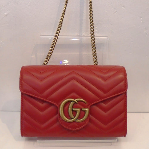 This Gucci Marmont WOC is red with gold hardware which includes the front Gucci Logo and the shoulder chain. The interior of this bag is black with a middle zippered compartment.