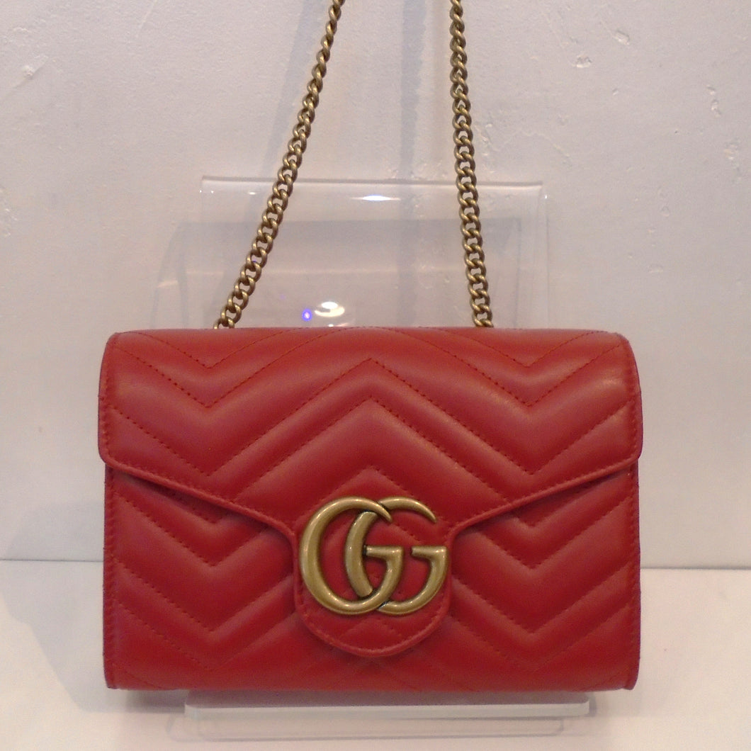 This Gucci Marmont WOC is red with gold hardware which includes the front Gucci Logo and the shoulder chain. The interior of this bag is black with a middle zippered compartment.