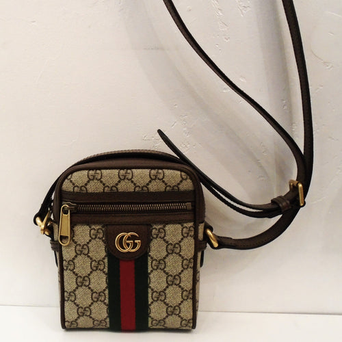 This Gucci Vintage Sherry Line Crossbody has the original Gucci pattern with a zipper pocket on the front of the bag. It has the GG logo in gold hardware on the front of the bag with a ribbon sized strip running from it to the other side of the bag.  The strip has dark green on either side with sherry color running through the middle.  It has a sturdy darkbrown crossbody strap. The interior of this bag is white.