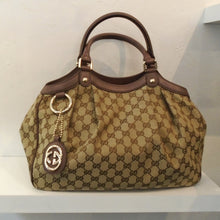 Load image into Gallery viewer, This Gucci Vintage Sukey Medium Tote is in the original Gucci pattern with dark brown trim. It  has two half moon shaped carrying handles. It also has a key ring with the Gucci logo in gold on it, hanging from a ring on the front of the bag. The interior of this bag is cream.
