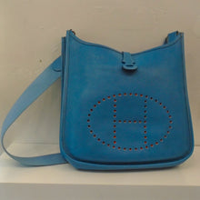Load image into Gallery viewer, This Hermes Vintage Blue Evelyne PM Clemence Leather bag has the perforated Hermes logo on the fron of the bag and has silver hardware.
