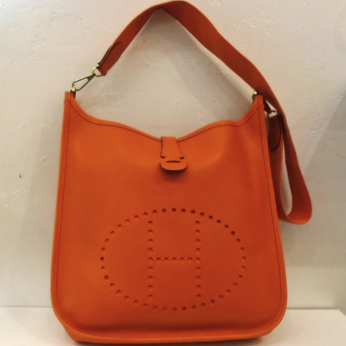 This Hermes Orange Evelyne Beau Epsom Leather GM has the perforated Hermes design on the front of the bag. It has gold hardware and a wide shoulder strap.