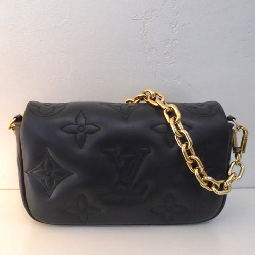 This Louis Vuitton Vintage Black Bubblegram Wallet has large embossed monogram. It has gold hardware which includes a heavy chain which is detachable. It also includes a guitar strap which is also detachable. The interior of this bag is black.