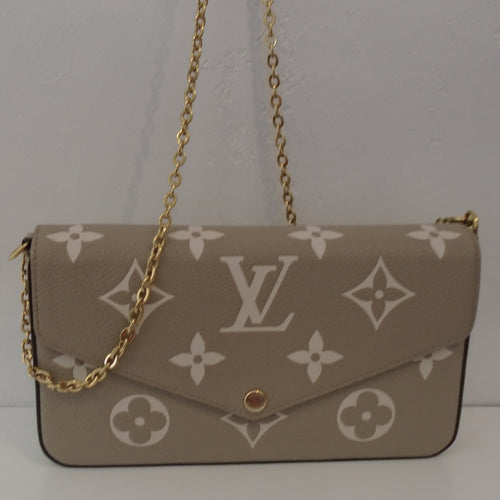 This Louis Vuitton Vintage Bicolor Empreinte Leather Felicie is in a cream brown background with large white Louis Vuitton Monogram. It has gold hardware which includes the Shoulder Chain. It contains a credit card holder and a zippered pouch. 