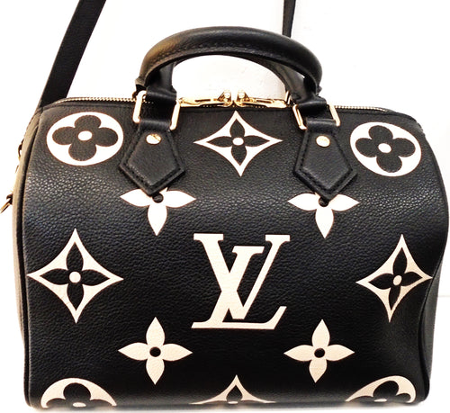 This Louis Vuitton Vintage Bicolor Empreinte Leather Speedy 25 is black with cream colored monogram. It has double carrying handles and a shoulder strap. The zipper meets at the top center with double pull tabs. This bag's interior is red.