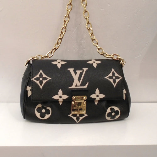 This Louis Vuitton Vintage Bicolor Favorite MM has the large monogram in cream over a black background of Empreinte Leather. It has gold hardware and comes with a detachable strap. This bag has two pleats underneath the front flap of the bag. The interior is a soft black.