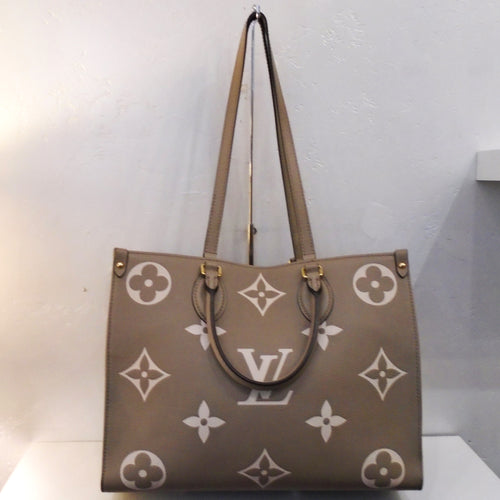 This Louis Vuitton Vintage Bicolor On The Go MM Empreinte Leather is taupe with cream colored large monogram. It has gold hardware, hand carrying handles and double shoulder straps. The interior of this bag is taupe also.