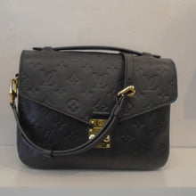 Load image into Gallery viewer, This Louis Vuitton Black Empreinte Leather Metis Pochette is imprinted with the regular size monogram. It has gold hardware, a carrying handle and shoulder strap. This bag has a back outside zipper and the interior is a light brown with dark brown stripes. 
