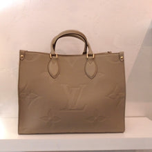 Load image into Gallery viewer, This Louis Vuitton Vintage Beige Empreinte Leather On The Go MM is in the large original Louis Vuitton monogram pattern. It has gold hardware and double carrying handles. The interior of this bag is beige also.
