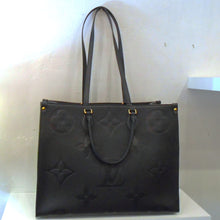 Load image into Gallery viewer, This Louis Vuitton Vintage Black Empreinte On The Go GM has the large monogram design imprinted on the front and back while the sides of the bag have the smaller monogram pattern.  This bag includes both double carrying handles and double shoulder straps. It has gold hardware and  the interior of the bag is a soft camel.
