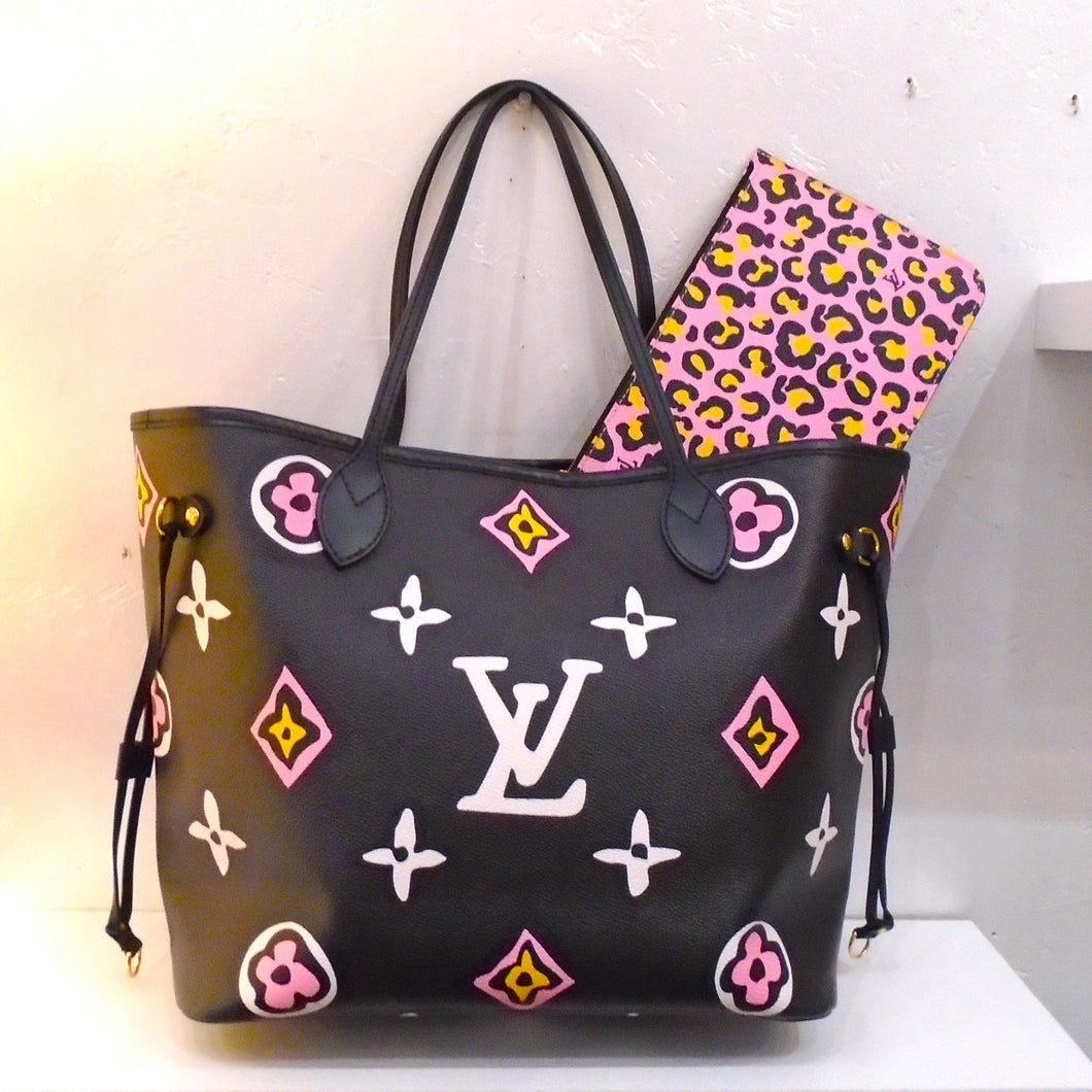 This Louis Vuitton Vintage Black Wild At Heart Neverfull MM With Pochette has large monogram in white, pink and yellow. The inside of the bag is gray with black leopard spots. This bag comes with a  Pochette that is pink with yellow cheetah spots.