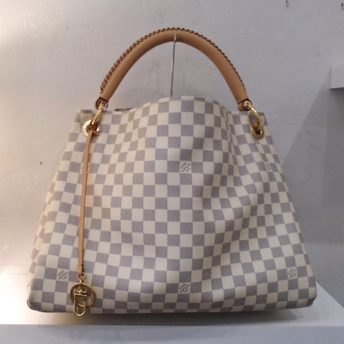 This Louis Vuitton Vintage Damier Azur Artsy MM has camel trim and gold hardware. It has a thick leather handle which has a braided design and a key ring attached to the front of the bag. This bag has a beige interior.