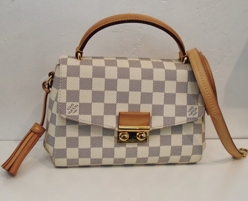 This Louis Vuitton Damier Azur Croisette has camel trim which includes a leather tassel  on the left  side of the bag, a carrying handle and the crossbody strap. It has gold hardware and the interior is Ballerina Pink.