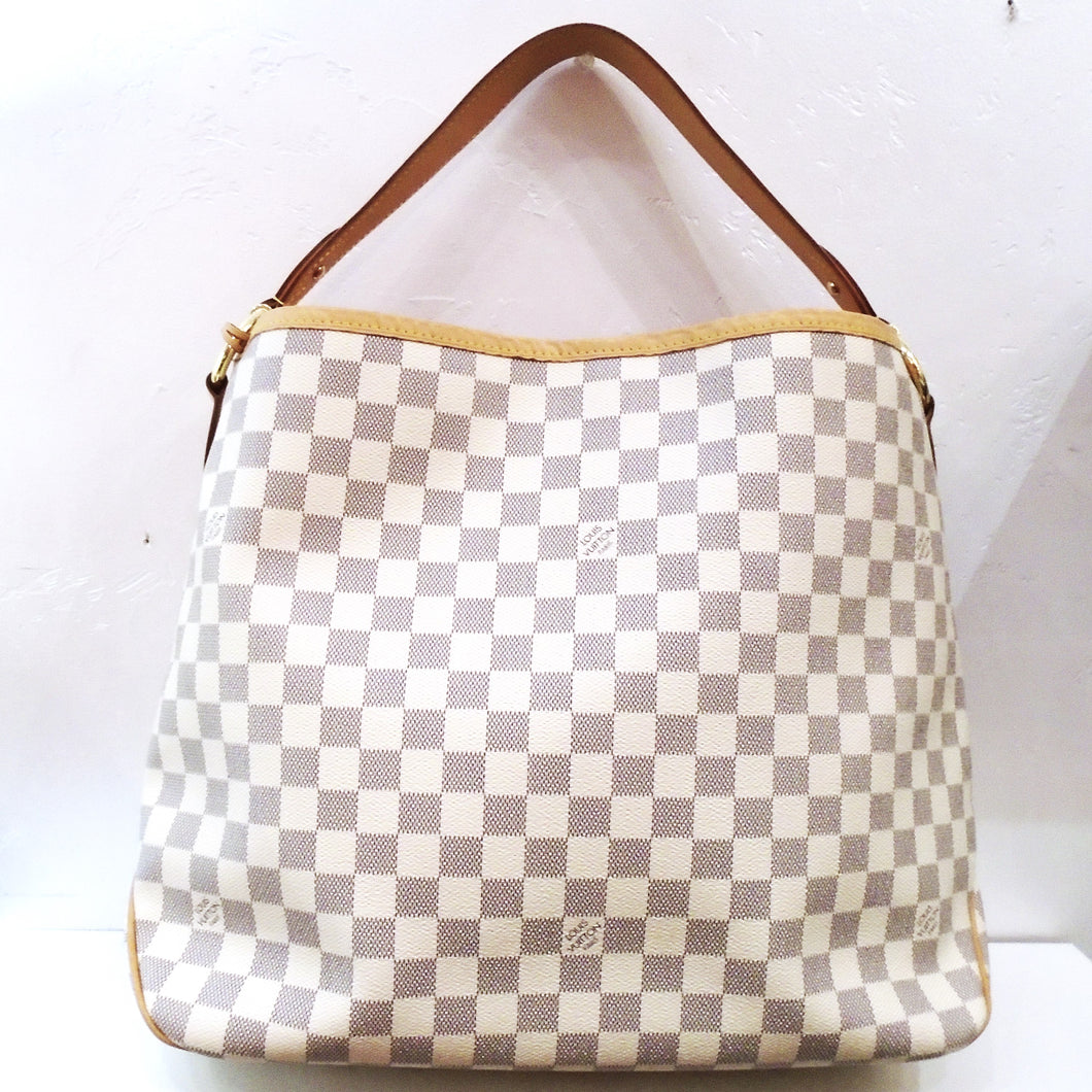 This Louis Vuitton Vintage Damier Azur Delightful MM has camel trim and gold hardware. The interior of this bag is pink with purple verticle lines.